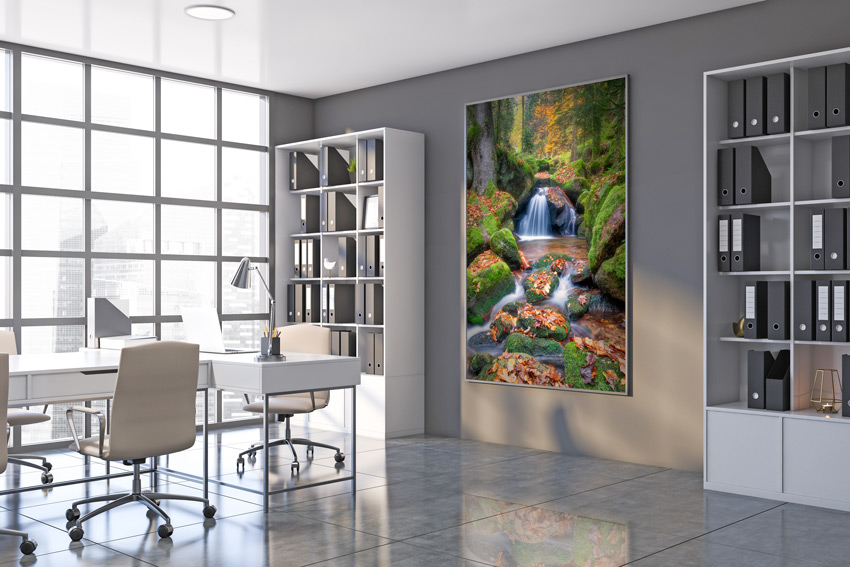 An einer Bürowand mit großer Glasfront, Schreibtischen hängt ein Heimatfoto aus dem Schwarzwald, es zeigt einen kleinen Bach in mitten eines Waldes mit einem kleinen Wasserfall