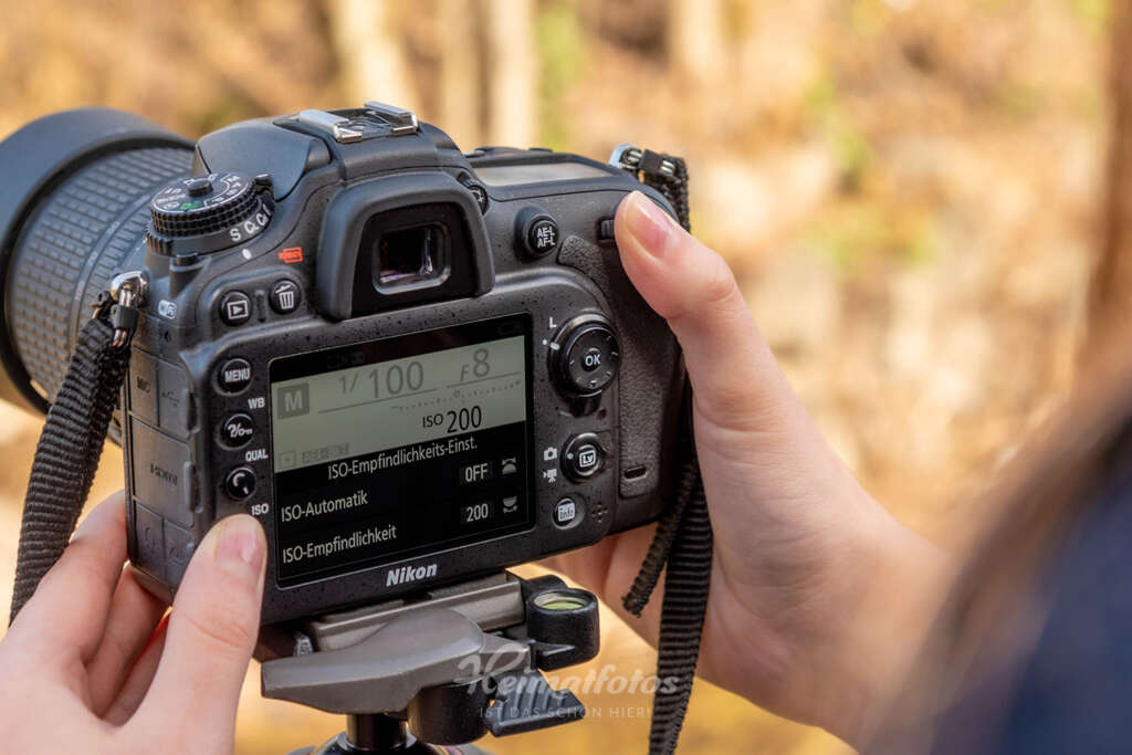 Eine Frau stellt den ISO-Wert an einer Nikon Spiegelreflexkamera über das Display auf ISO 200