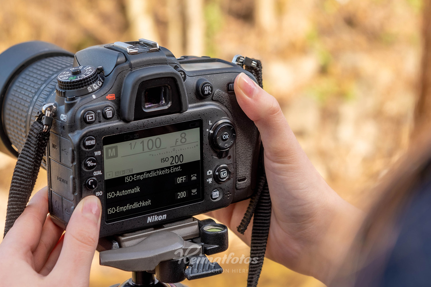 Eine Frau stellt den ISO-Wert an einer Nikon Spiegelreflexkamera über das Display auf ISO 200