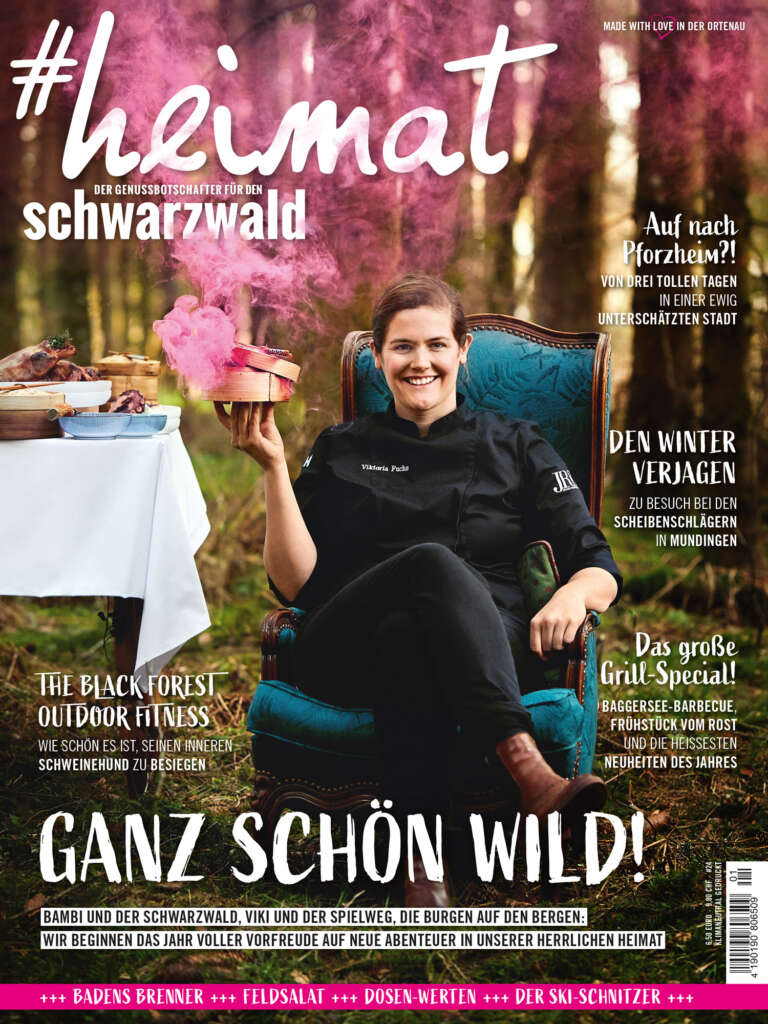Titelblatt des Magazins "#heimat – Der Genussbotschafter für den Schwarzwald", Ausgabe 01/2021 - Titelbild: Viktoria Fuchs, vom Hotel Spielweg im Münstertal, sitzt auf einem Sessel im Wald und hält eine rauchende Schüssel in der Hand · In dieser Ausgabe geht es um Urlaub in Pforzheim, The Black Forest Outdoor Fitness, das Scheibenschlagen in Mundingen und ein großes Grill-Special