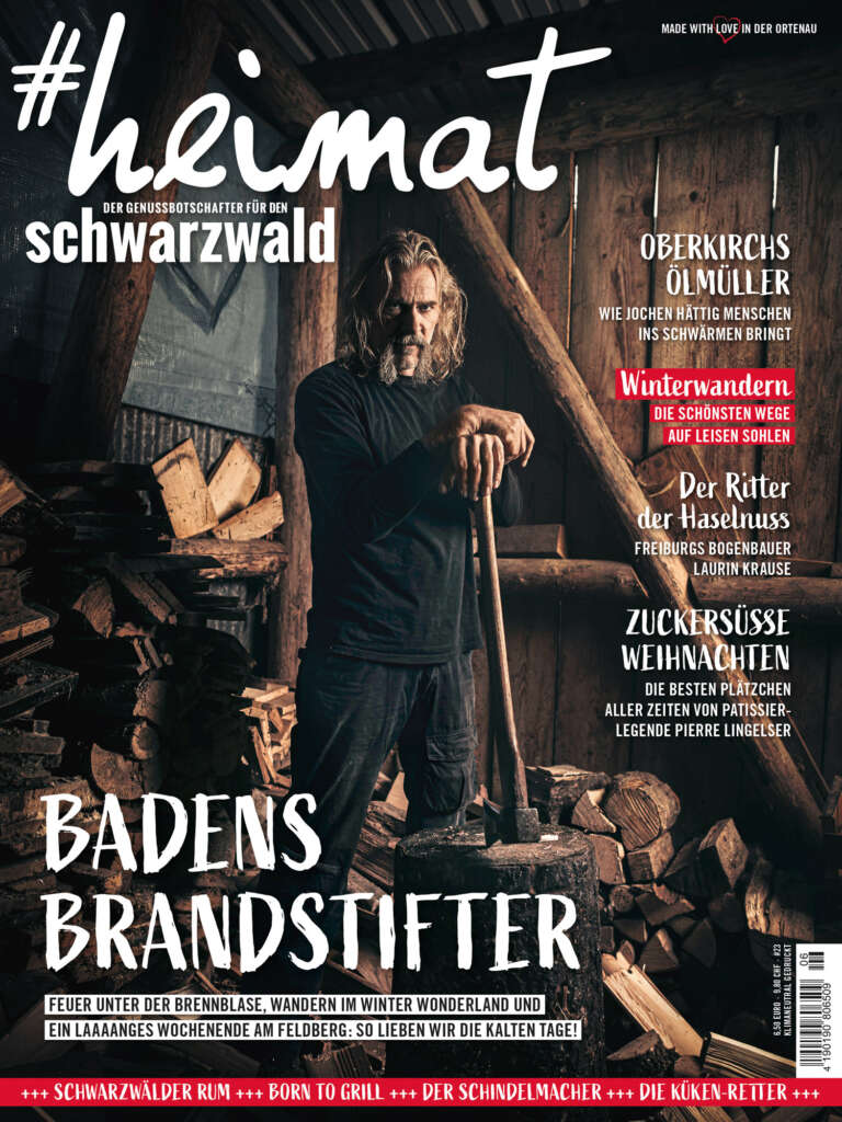 Titelblatt des Magazins "#heimat – Der Genussbotschafter für den Schwarzwald", Ausgabe 06/2020 · Mann mit Axt steht in einem dunklen Holzschuppen, in dieser Ausgabe geht es um Oberkirchs Ölmüller, Winterwandern im Schwarzwald, Den Ritter der Haselnuss, Zuckersüße Weihnachten und Badens Brandstifter