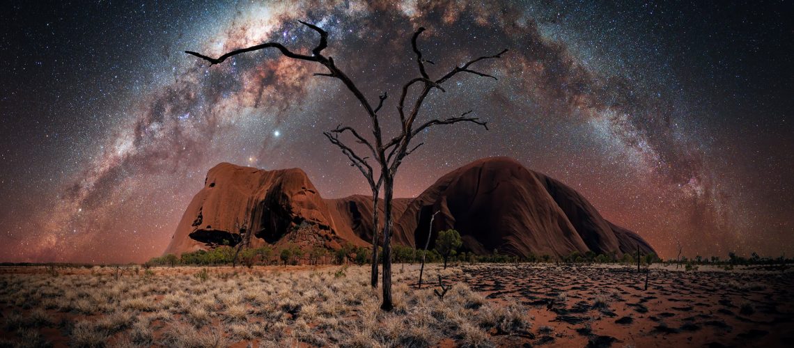 Uluru`s Night von Nacht- und Astrofotograf Stefan Liebermann - Night Panorama of the Uluru in Australia. In the foreground you can spot burned down trees and contrast between dry gras and burned down regions. In the sky is the milky way arch.